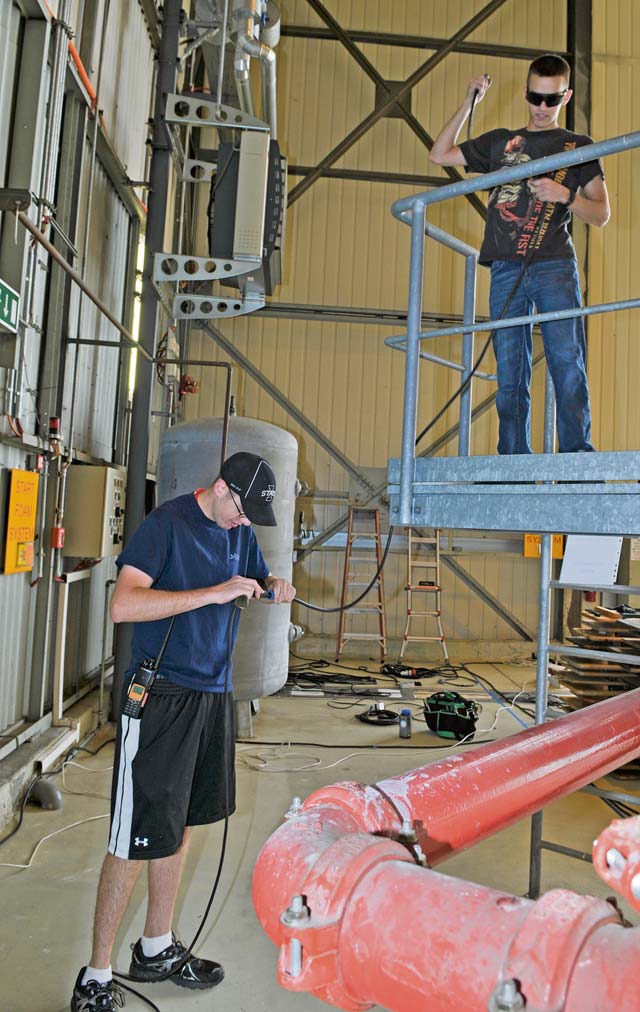 Senior Airman Andrew Miller and Airman 1st Class Brandon Daniel, 86th Communications Squadron radio frequency transmissions  systems technicians, install speakers in a hangar for the Ramstein Welfare Bazaar.