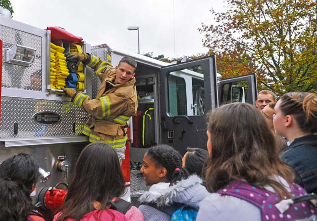 Airman 1st Class Jacob Frost, 86th Civil Engineer Squadron Fire Department firefighter, shows Ramstein Middle School students the hoses on a fire truck during Fire Prevention Week. The students learned about the equipment the 86th CES firefighters use during training and real-world  situations.