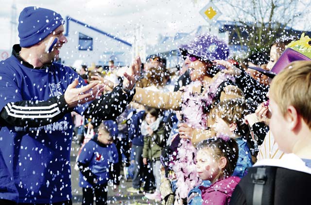 Photo by Senior Airman Hailey HauxA Fasching parade member throws confetti at the crowd as he walks by. 
