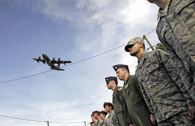 Photo by Staff Sgt. Sara KellerA C-130J Super Hercules flies over a formation of U.S. Air Force Airmen as they march at a ceremony in Picauville.