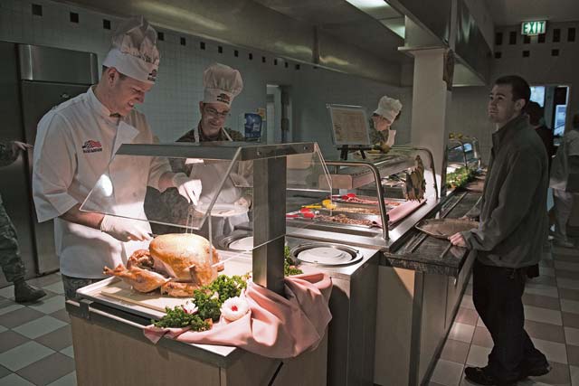 Col. Leslie Smith (left), 86th Airlift Wing vice commander, carves a turkey at the Rhineland Inn dining facility Nov. 28 on Ramstein. Base leadership volunteered to serve a Thanksgiving meal to Airmen and their families as a way to boost morale and provide a low-cost option. Turkey, sweet potatoes, mashed potatoes, two types of gravy, green beans and corn were some of the Thanksgiving items served as part of this Thanksgiving holiday tradition.