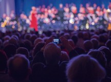 An audience member takes a photo of the U.S. Air Forces in Europe Band and the Rheinland-Pfalz International Choir as they perform. The band and choir performed and sang a wide variety of holiday songs in English and German.