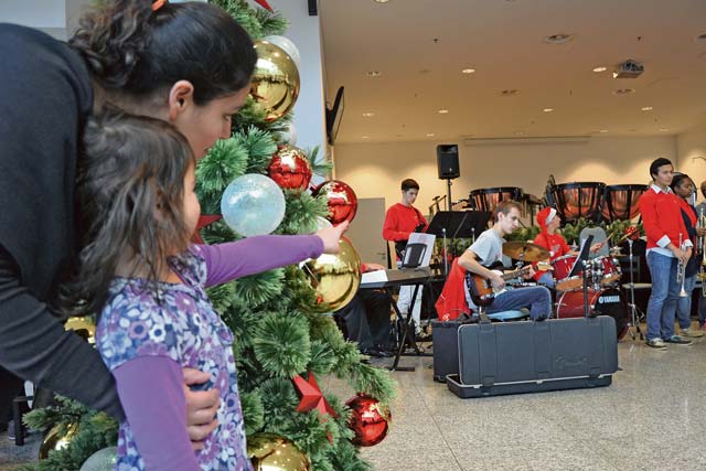 Photo by Rick ScavettaMaria Frutiger and her daughter, Natalia, 5, listen to the  Kaiserslautern High School band perform during this year’s Holiday Spirit Drive, where Army Air Force and Marine Corps groups collected donated gifts for needy families in the KMC.