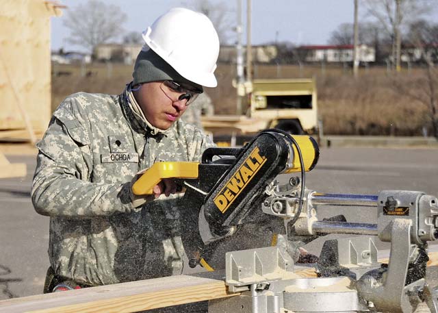 Spc. Francisco Ochoa, a carpentry and masonry specialist with the 902nd Engineer Company (Vertical), 15th Engineer Battalion, 18th Engineer Brigade, 21st Theater Sustainment Command, saws a wooden board during a construction project at the Mihail Kogalniceanu Air Base Passenger Transit Center Jan. 14.