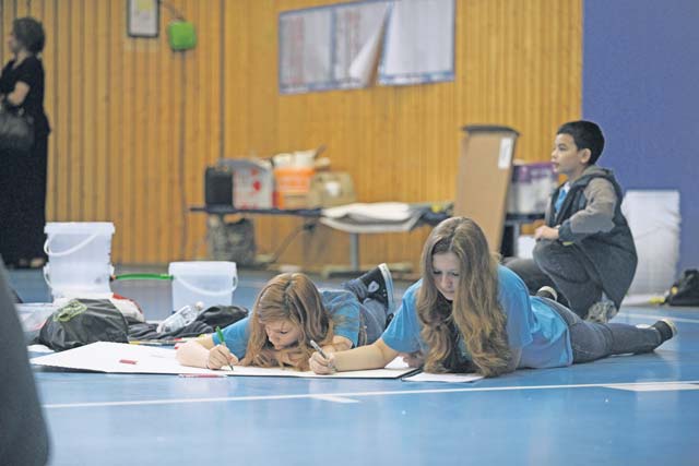 Photo by Senior Airman Jose L. LeonElyse Bollenberg (left), daughter of Tech. Sgt. Luke Bollenberg, and Elise Tyler, daughter of Mary Tyler, work together on a poster during the STEMposium.