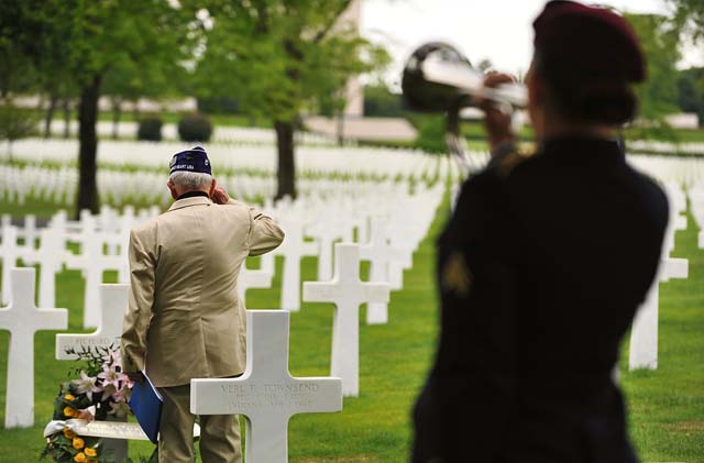 Photo by Senior Airman Hailey HauxWorld War II veteran Leslie Cruise salutes the grave of Pvt. Richard Vargas while Army Sgt. Jeannette Mason, 5th Quartermaster Theater Aerial Delivery Company parachute rigger, plays taps during a wreath laying ceremony June 2, 2014, at the Lorraine American National Cemetery and Memorial in St. Avold, France. Vargas saved Cruise’s life 70 years ago during the invasion of Normandy.