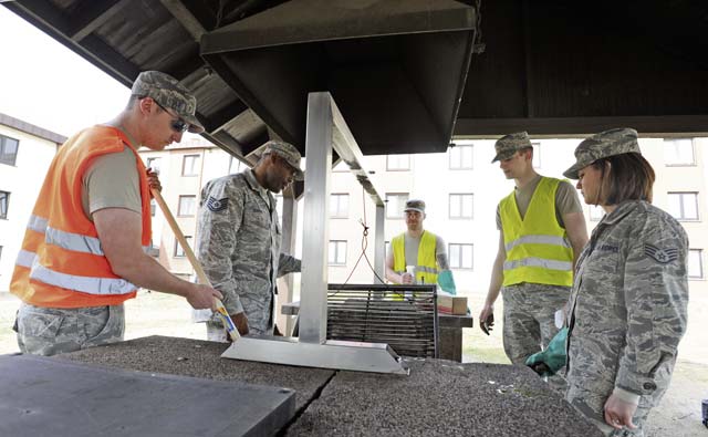 Airmen dorm leaders from the Ramstein Dorm Reception Center assist Airmen assigned to bay orderly with cleaning a grill April 2.