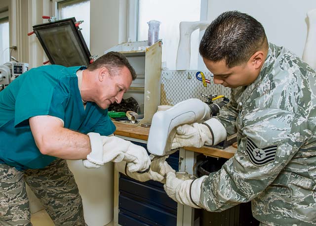 Photo by Maj. Julie JohnsonBrig. Gen Patrick X. Mordente (left), 86th Airlift Wing commander, and Tech. Sgt. Pompilio Alfaro Jr., 86th Medical Support Squadron brace shop NCOIC, pull plastic over a patient’s leg mold to create an ankle foot orthotic device for drop foot during a Landstuhl Regional Medical Center visit Sept. 27. This device is used to control instabilities in the lower limb by maintaining proper alignment and controlling motion.