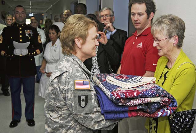 Photo by Phil A. JonesCol. Judith Lee, Landstuhl Regional Medical Center commander, presents Maria Fox-Meehan with a handmade quilt of valor during the dedication ceremony of The Thomas Meehan Suite. 