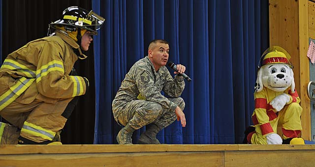 Airman 1st Class Brice Haylett, 86th Civil Engineer Squadron firefighter, Master Sgt. Paul Luevano, 86th CES assistant chief of fire prevention, and Sparky the fire dog demonstrate how to crouch down when there is a fire in the room.