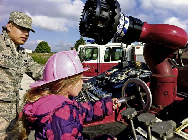 Photo by Senior Airman Chris WillisAirman 1st Class James Perez-Reyes, 86th Civil Engineer Squadron firefighter, shows Delilah Willis some of the fire trucks’ capabilities during Job Shadow Day May 16 on Ramstein. Job Shadow Day gave children of service members and civilians working in the KMC a chance to see what their parents’ jobs provide to the local and global communities.