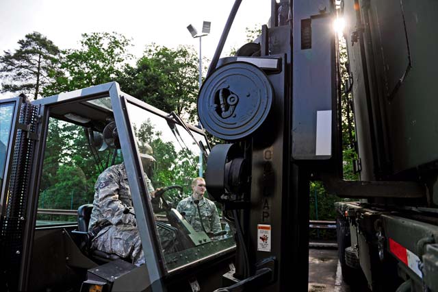 Staff Sgt. Hector Galan (left), 86th Vehicle Readiness Squadron assistant NCO in charge of material handling equipment maintenance, uses a forklift to hoist a pallet from a trailer while Staff Sgt. Matthew Creighton, 86th VRS MHE maintainer, spots him during a safety stand-down day June 28 on Ramstein.
