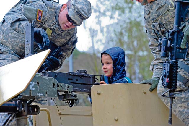 Pfcs. Tayler Woodson and Alexander Cunningham, 230th Military Police Company, supervise children on a Humvee.