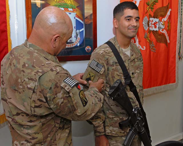 Command Sgt. Maj. Ismael Rodriguez, command sergeant major of Deputy Command Support Operations in Kabul, Afghanistan, presents his son, Spc. Francisco Rodriguez, an information technology specialist from the 580th Signal Company located in Schweinfurt, Germany, with the 7th Signal Brigade combat patch during a ceremony March 26 on Bagram Airfield in Afghanistan.