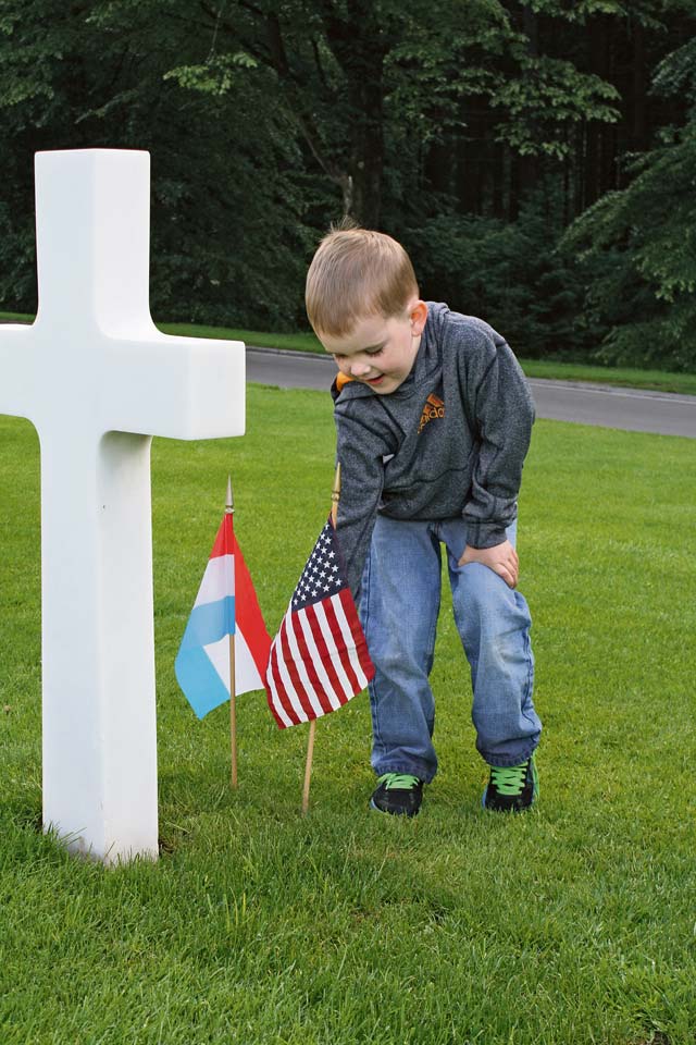 Blake Webb, son of Tech. Sgt. Robert Webb, 86th Airlift Wing Public Affairs NCO in charge of broadcasting, plants a flag during a memorial service.