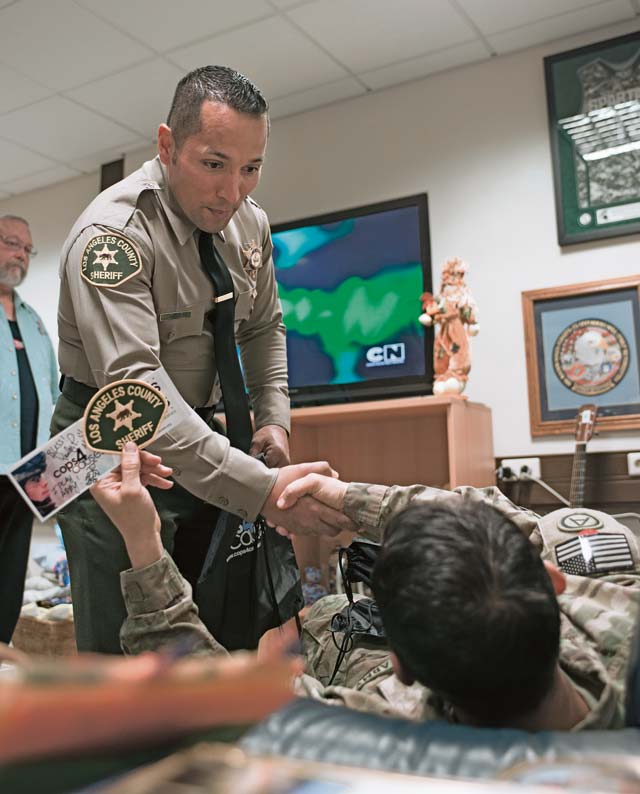 Christopher Landavazo, Cops 4 Causes president, shakes hands with a wounded military member, Nov. 24 on Ramstein. Along with visiting wounded warriors, Cops 4 Causes toured various facilities around the KMC.