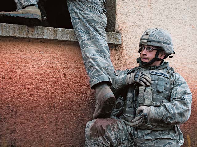 Photo by Senior Airman Damon KasbergSenior Airman Kenneth Rivera-Ithier, 514th Security Forces Squadron defender, assists a team member into a building during an urban operations base security operations course. More than 100 Airmen participated in the course to sharpen their skills and come together as a team.