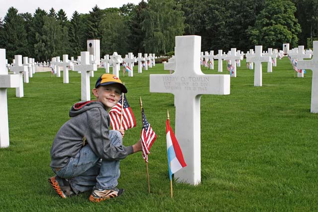 Lucas Webb, a Cub Scout from Pack 243 and son of Tech. Sgt. Robert Webb, 86th Airlift Wing Public Affairs NCO in charge of broadcasting, plants a flag during a memorial service at the Luxembourg American Cemetery and Memorial.
