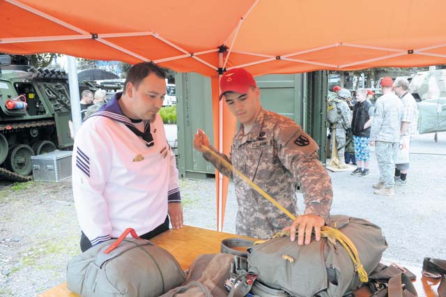 Pfc. Taylor Trombley, a parachute rigger assigned to the 21st Theater Sustainment Command’s 5th  Quartermaster Company, shows German Cpl. Andreas Heise, a member of the Rheinland-Pfalz Frigatte (naval group), Army parachute equipment during the Rheinland-Pfalz Tag June 22.