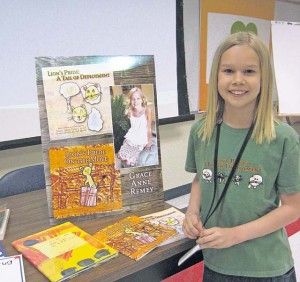 Courtesy photo Grace Anne Remey poses for a photo in front of her book display at the Ramstein Library. She has published two children’s books designed to help families cope with the constant change of the military lifestyle.
