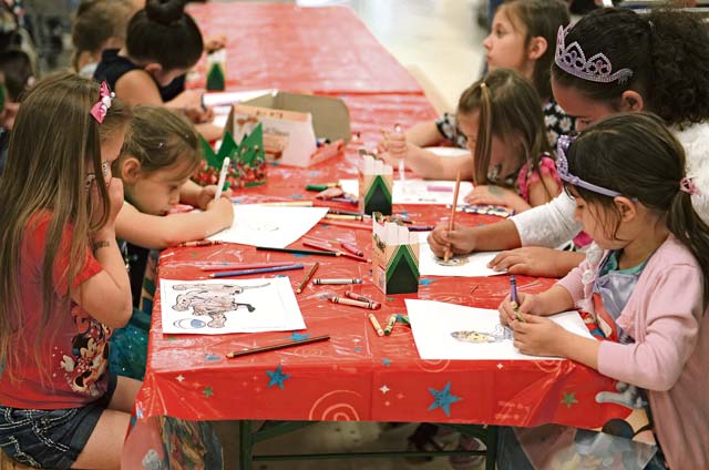 A group of children color cartoon characters during the arts and crafts portion of the opening of the toy collection May 17 at the Ramstein Base Exchange. The opening included prize trivia, a  storybook reading, a costume contest and other activities to entertain the children who attended.