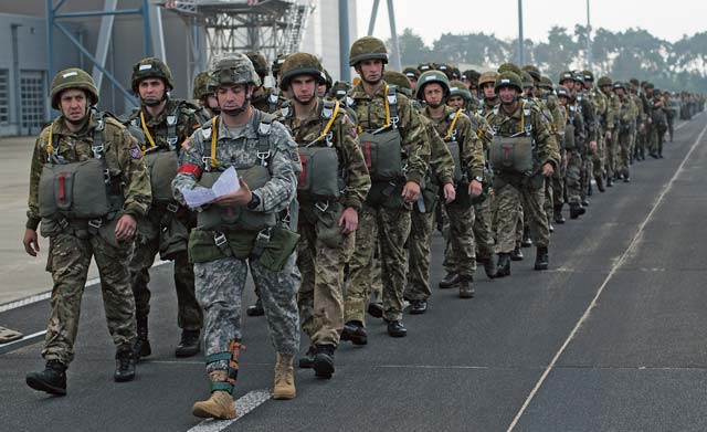 Photo by Senior Airman Damon KasbergU.S. Army Sgt. 1st Class Luis R. Rodriguez, 82nd Airborne Division U.S. Army Advance Airborne School senior instructor, leads paratroopers to their aircraft Sept. 20, 2014, in Eindhoven, the Netherlands, during a re-enactment of the jumps made during Operation Market Garden.