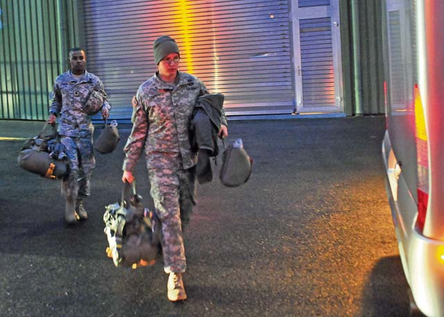 Two paratroopers assigned to the 21st Theater Sustainment Command’s 5th Quartermaster Detachment carry their parachutes to a bus bound for Ramstein Nov. 7.