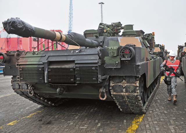 Pvt. Cori A. Berwanger, a military police Soldier with the 21st Theater Sustainment Command’s 615th Military Police Company, 709th Military Police Battalion, 18th Military Police Brigade, patrols between lines of M1 Abrams tanks Jan. 24 at Bremerhaven Port.