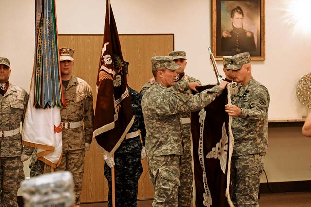 Army Col. Jeff Clark (left), Europe Regional Medical Command commander and U.S. Army Europe command surgeon, and Command Sgt. Maj. Robert Luciano, ERMC command sergeant major, unfurl the ERMC flag during an uncasing ceremony April 24 at the Community Activity Center on Sembach Kaserne. The ceremony officially marked  the relocation of ERMC headquarters from Heidelberg to Kaiserslautern.