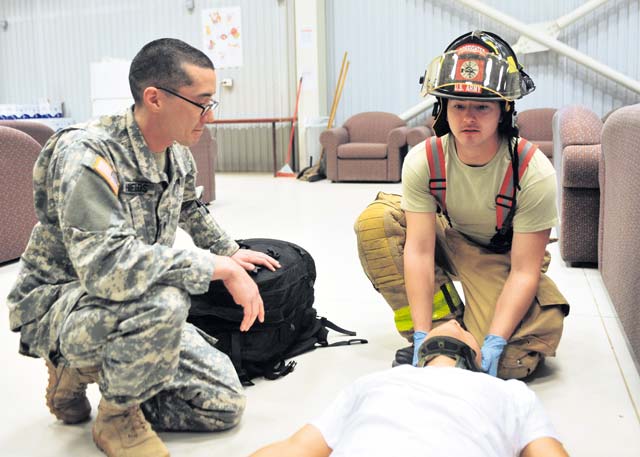 Spc. Thomas P. Shields (left), medic with the 21st Theater Sustainment Command’s 557th Medical Company, 421st Multifunction Medical Battalion, 30th Medical Brigade, and Pfc. Michael L. Warren, firefighter with the 513th Firefighting Detachment, 20th Engineer Brigade, render first aid to a simulated casualty during an active-shooter exercise March 20 on Mihail Kogalniceanu Air Base, Romania.