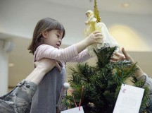 Master Sgt. Timothy Bliefnick, 86th Comptroller Squadron and Wing Staff Agencies first sergeant, helps his daughter, Annabella, place an angel decoration on top of a tree in the Kaiserslautern Military Community Center Nov. 17 on Ramstein. The 13 trees set up around the KMC to accept donations are meant to be used to provide financial relief to military families during the holiday season.