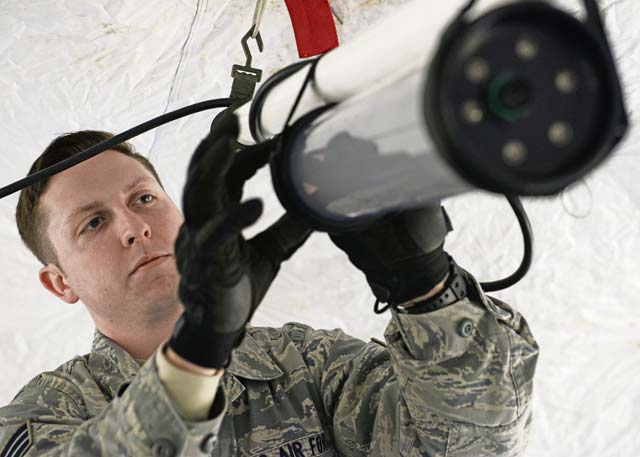 Senior Airman Brian Purcell, 435th Contingency Response Group specialist, adjusts the cords on a light fixture to provide light for a tent during indoctrination training Feb. 24.