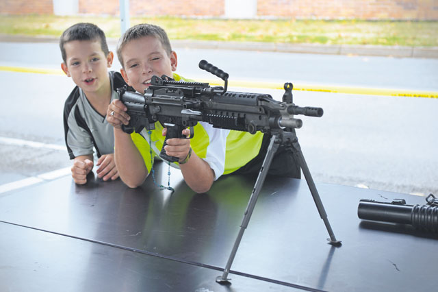 Weston and Kaiden Bodkin, sons of Staff Sgt. Clayton Bodkin, 700th Contracting Squadron  unit deployment manager, interact with weapons on display during the 2013 Day for Kids.