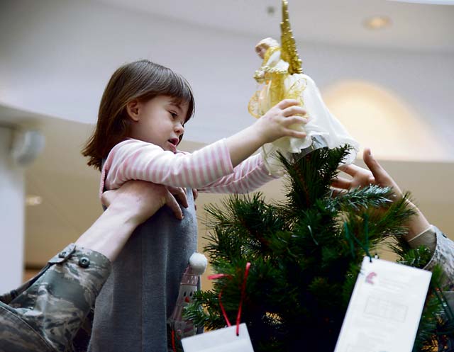 Photo by Senior Airman Timothy MooreMaster Sgt. Timothy Bliefnick, 86th Comptroller Squadron and Wing Staff Agencies first sergeant, helps his daughter, Annabella, place an angel decoration on top of a tree Nov. 17, 2014, in the Kaiserslautern Military Community Center on Ramstein.