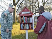 Lt. Col. Mike Sullivan, U.S. Army Garrison Baumholder commander, listens as Lorne Huxtable explains the concept of the Little Free Library. Huxtable’s desire to improve his reading skills and spread literacy throughout the Baumholder community inspired him to provide this free service.