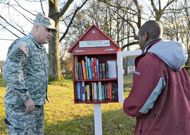 Lt. Col. Mike Sullivan, U.S. Army Garrison Baumholder commander, listens as Lorne Huxtable explains the concept of the Little Free Library. Huxtable’s desire to improve his reading skills and spread literacy throughout the Baumholder community inspired him to provide this free service.