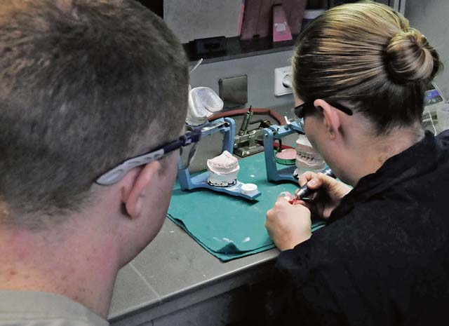 Tech. Sgt. Candice Reffitt, 86th Dental Squadron dental laboratory technician, trains Senior Airman Cody Murphy on laboratory operations Jan. 15 on Ramstein. Reffitt shows Murphy how to shape a dental implant to fit a particular patient. 