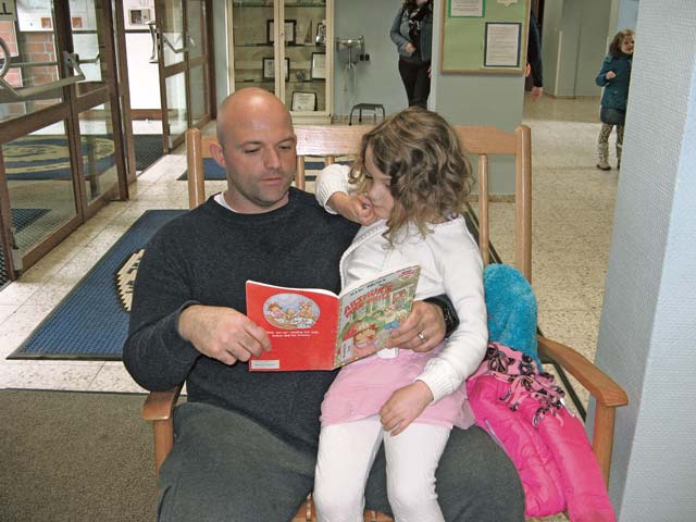 Courtesy photoReading time at LEMSStaff Sgt. Charles Rhodes and his daughter, Chiara, read together in front of the Landstuhl Elementary/Middle School library.