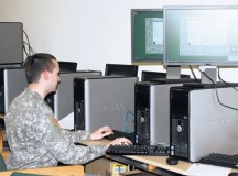 Amongst a battery of computers, Spc. Ryan Clark works on re-imaging a computer.