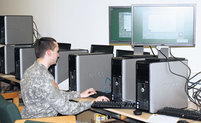 Amongst a battery of computers, Spc. Ryan Clark works on re-imaging a computer.