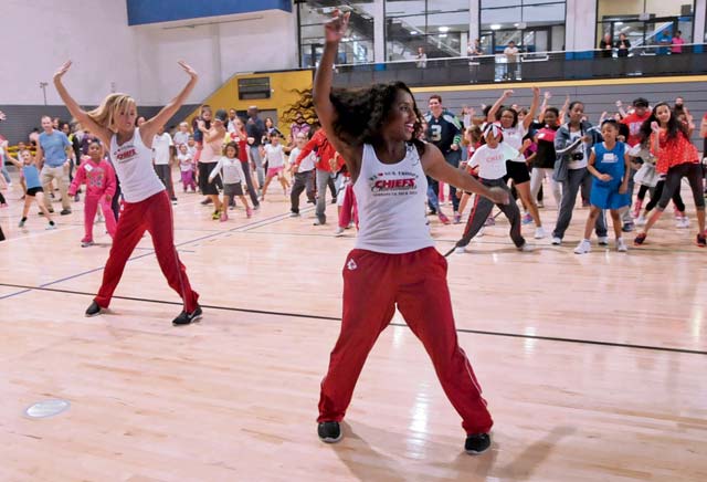 Kansas City Chiefs cheerleaders Krystal (front) and Hayley lead children and parents from the KMC in a dance during a cheerleading clinic Oct. 11 at the Ramstein Southside Fitness Center.