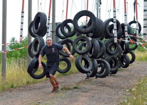 A contestant battles his way through one of the tire obstacles on the course.