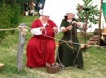 Females in medieval costumes present old skills during the medieval market.