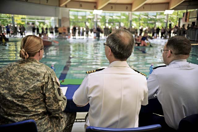 Three judges watch as Battle of the Battleships participants race for the championship title at the Ramstein Aquatic Center.