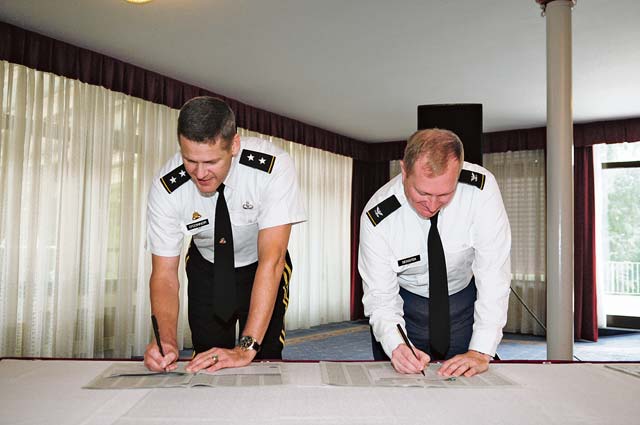 Photo by Spc. Iesha HowardMaj. Gen. John R. O’Connor (left), commanding general of the 21st Theater Sustainment Command, and Col. Bryan Decoster, commander of U.S. Army Garrison Kaiserslautern, sign their contribution forms for the Combined Federal Campaign during the CFC Fiscal Year 2014 kickoff ceremony Sept. 16 at Armstrong’s Club on Vogelweh Military Complex. The CFC gives military members the opportunity to donate to a wide variety of charities of their choice, including organizations that provide benefits to service members and their families.