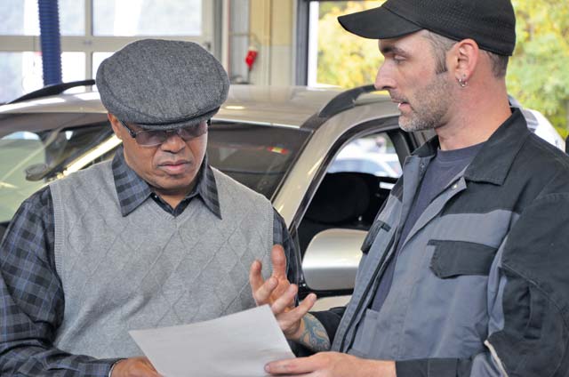 Photo by Elizabeth BehringDanny Sneed (right), a wreck assistant at Pulaski Auto Skills, goes over Andres J. Martinez Javier’s worksheet after performing a free check on Javier’s car Oct. 25 during U.S. Army Garrison Rheinland-Pfalz’s biannual Vehicle Inspection Day. Javier works at the U.S. Army Medical Materiel Center, Europe, in Pirmasens. Sneed said the two most common errors he sees during auto checks are over-inflated tires, which can wear out quickly and be dangerous, and customers who don’t get their oil routinely changed.