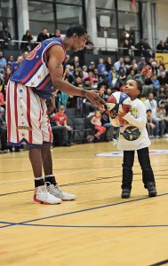 Kris “Hi-Lite” Bruton, Harlem Globetrotter forward, helps a fan make a basket during a game.