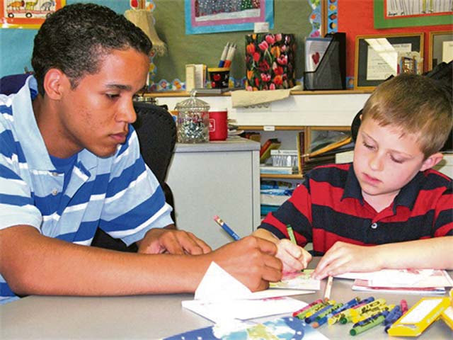 Courtesy photoBrice Relaford, Ramstein High School Deployment Buddies mentor, helps a Ramstein Elementary School student draw a card for his father Jan. 29 on Ramstein. High school and elementary school students of deployed service members come together once a month to share experiences and provide comfort to one another through the Deployment Buddies Program during their parent’s deployments. 