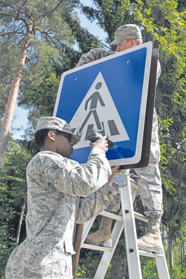 Photo by Senior Airman Chris WillisAirmen 1st Class Keandre Hall and Tyler McCaslin, 786th Civil Engineer Squadron structure technicians, replace a crosswalk sign. The 786th CES manages more than 10 million square feet of airfield, more than 4,700 acres of land on Ramstein and 19 other geographically separated units.