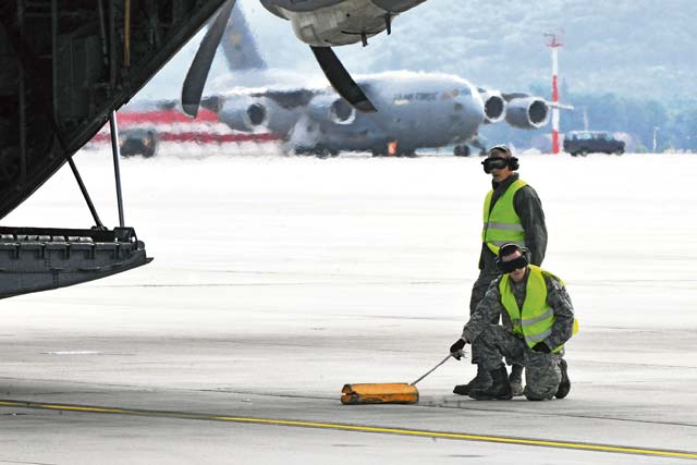 Photos by Senior Airman Chris WillisAirman 1st Class Matthew Smith and Senior Airman Robert Greer, 721st Aerial Port Squadron ramp service specialists, participate in an engine-running offload.